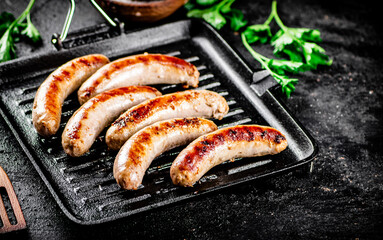Grilled sausages in a frying pan with parsley. 