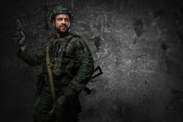 Fototapeta na wymiar Contemporary soldier dressed in green protective uniform with rifle and handgun.