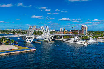 Fototapeta na wymiar A view of boats sailing through the bridge across the Stranahan River from Port Everglades, Fort Lauderdale on a bright sunny day