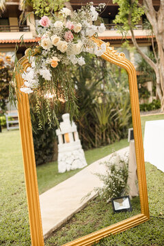 A welcome mirror board sign with a beautiful flower and rustic decoration, standing in front of wedding entrance.