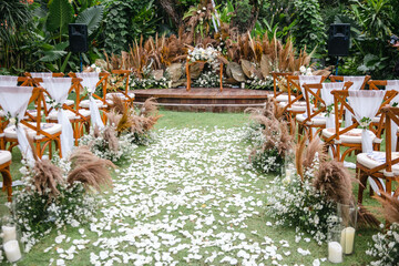 Beautiful outdoor wedding decoration with dry plants, flowers, candles and accessories in garden. Natural, shabby, boho wedding decor. Open air wedding banquet on green lawn