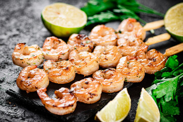 Grilled shrimp on a stone board with parsley and lime.