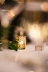 Beautiful table setting decorated with lighted candles, tableware, flowers, accessories for a party, wedding reception, gala banquet or other holiday event.