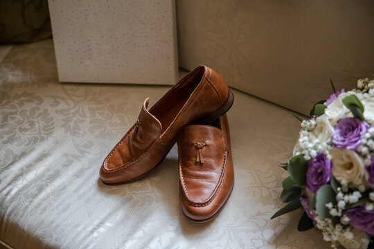 Classic brown male shoes with blank empty board on the bed. Wedding details and accessories.