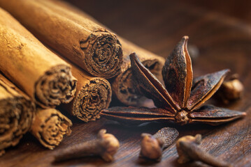 Organic Raw Brown cinnamon sticks Anise star spice fruits and seeds on old wooden table wood stump trunk outdoor walnut plate spoon closeup macro Food Background Vintage Selective Focus.