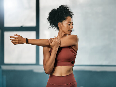 Fitness, black woman or girl in gym stretching arms to warm up body or relax muscles for workout exercise. Wellness, focus or healthy sports athlete ready to start training or exercising in Atlanta