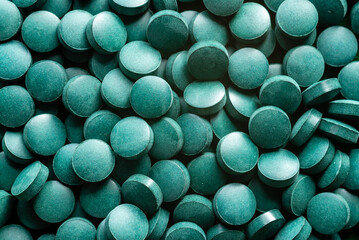 Green Organic Spirulina in algae pills tablets  bamboo wood  spoon rich in iron Close-up Super food concept healthy - obrazy, fototapety, plakaty