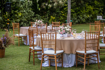 Beautiful outdoor wedding decoration in garden. Round tables decorated with flowers, candles and...