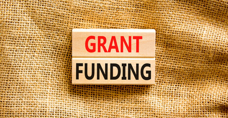 Grant funding symbol. Concept words Grant funding on wooden blocks. Beautiful canvas table canvas...