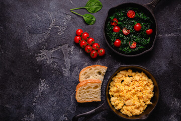 Cooked omelet and spinach with tomatoes in pans