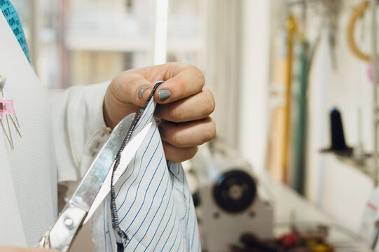 Close Up Of Female Hands Cutting The Edge Of The Fabric With The Scissors.