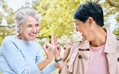 Elderly, women and middle finger at the park for fun, humor and silly while laughing together. Mature, friends and females with hand, emoji and gesture, playful and happy, smile and bonding in nature