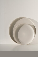 Two beige ceramic plates on a light background on a sunny day. Natural lighting