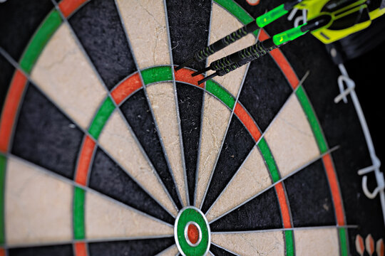 Three darts stuck in the Triple 20 of a dartboard. 180 points. Close-up of a dartboard.