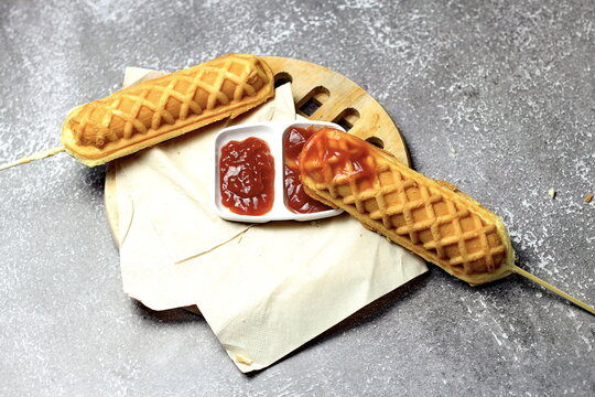Corn dogs waffle and ketchup on a gray table