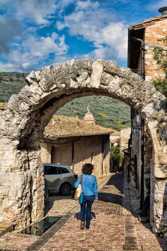 spello, italien - frau geht durch den antiken arco dei cappuccino