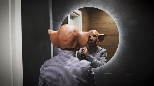  back view of creapy scary man with horror pig mask prepare for night put some perfume