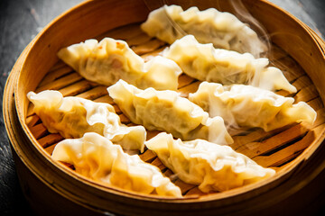 Dumplings gyoza in a bamboo steamer with hot steam. 