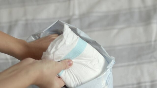 baby diapers in pack woman mother hand or bed finger counting throwing on blanket chaotic or in row arrangment.mom hand hold new diaper white no paint drawn close up 4k slow motion motherhood 