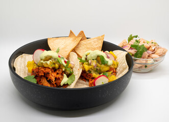 Healthy vegan jackfruit tacos in a black bowl on white background. 