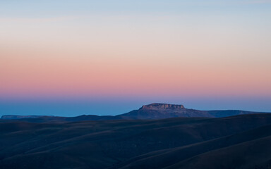 Panoramic view of magical magenta dawn over the Bermamyt plateau. Atmospheric dawn landscape with beautiful Bermamyt plateau is in the distance.