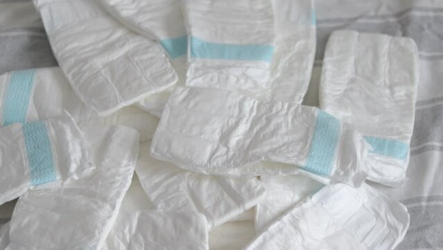 baby diapers in pack woman mother hand or bed finger counting throwing on blanket chaotic or in row arrangment.mom hand hold new diaper white no paint drawn close up 4k slow motion motherhood 