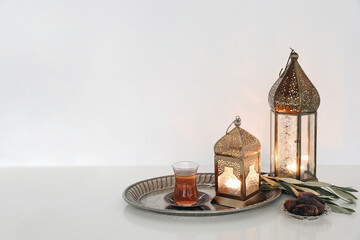 Festive Ramadan Kareem still life. Glowing Moroccan ornamental lanterns and glass cup with Turkish...