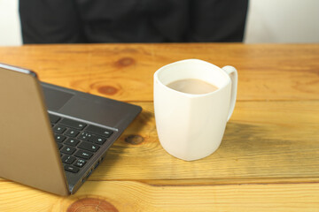 white mug with coffee next to a laptop