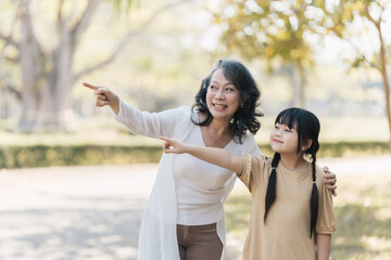 Grandmother and granddaughter pointing into the park, spend time in free time together