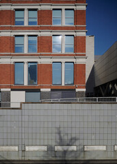 Modern building with red brick above an old tiled wall