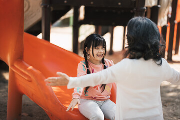 Little girl and her grandmother having fun at outdoor playground in the park