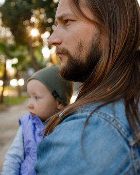 Dad and his toddler are walking in the park.