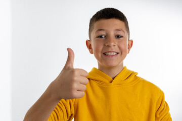 Young boy over isolated white background with thumbs up because something good has happened