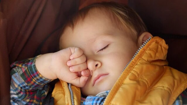 Portrait of cute little baby boy sleeping in stroller on sunny autumn day. Child development, kids resting, baby healthcare.