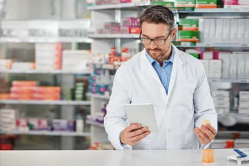 Foto op Canvas Pharmacist man, shop and reading with tablet, medicine, pills and counter for health, medication or sales. Medical professional, pharma expert and mobile digital tech in pharmacy with wellness app © Reese/peopleimages.com