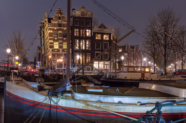 Beautiful old houses on the city waterfront of Amsterdam at sunset.