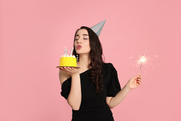 Coming of age party - 21st birthday. Woman holding delicious cake and sparkler and blowing number...