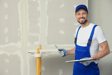 Professional worker with putty knives near wall. Space for text