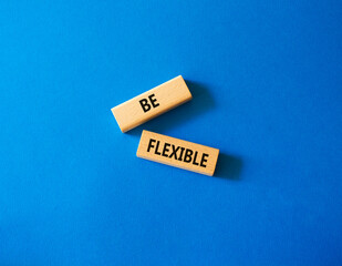 Be Flexible symbol. Wooden blocks with words Be Flexible. Businessman hand. Beautiful blue background. Business and Be Flexible concept. Copy space.
