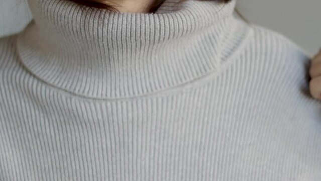 woman putting warm grey sweater pullover close up neck video slow motion autumn season.girl in wool clothes ready cold weather