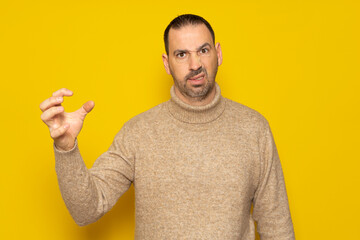 Bearded hispanic man wearing turtleneck over isolated yellow background doing cat claw gesture...