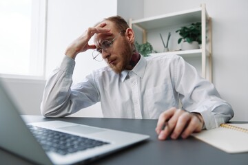 Fototapeta premium A man in a wheelchair a businessman in the office works, severe fatigue and emotional burnout, integration into society, the concept of work a person with disabilities