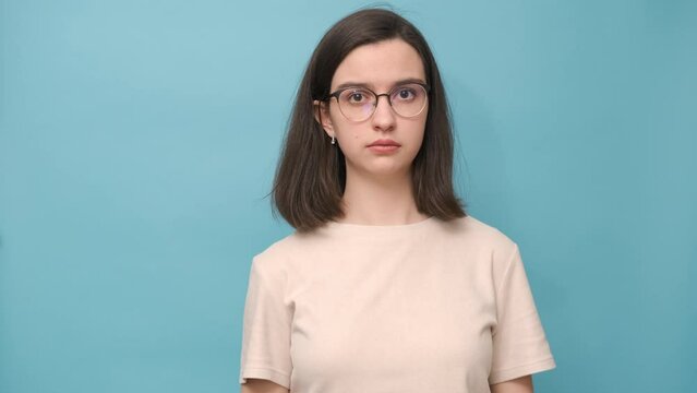 Portrait of a student girl with glasses and a beige blouse covering her ears, mouth, eyes, 4 K. Nonverbal communication. The girl shows that she sees nothing, hears nothing, will not tell anyone