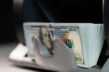 Close up of electronic cash counting machine. Counting money on bank automatic equipment. Banknotes of 100 dollar bills. Money counting machine, investment capital operations