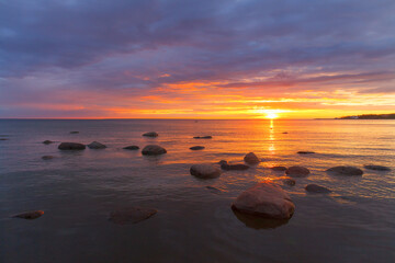 Fototapeta na wymiar The Baltic sea with golden sunset sky above, rocky seashore