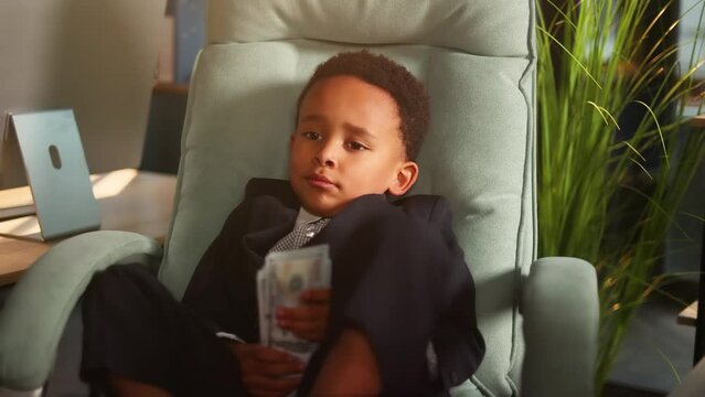 Portrait of successful little african american businessman kid child boss talk with his colleagues with stack of money dollars in the modern office workplace 