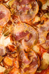 Close-up view on pizza topping with bacon, cheese and slices of pickled cucumber and onion