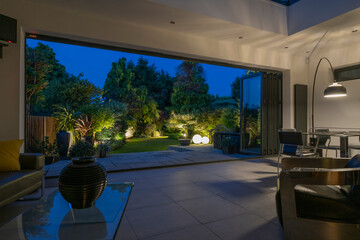 Beautiful garden and patio on a summer evening seen from stylish designer room through bifold doors.