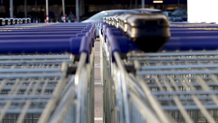 many trolley shopping cart with coin lock anti theft system outside in row sunny day different angles blue handle chain blocked carts,details.man analysis receipt prices money spent next to car