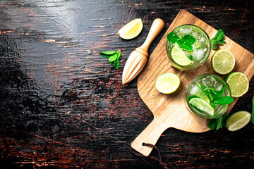 Mojito with pieces of lime on a cutting board.